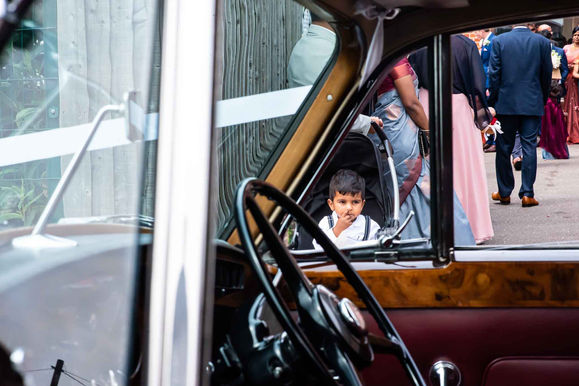 Young boy picks his nose as he waits for bride and groom to leave the church