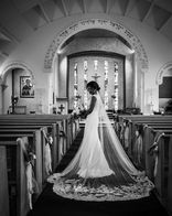 Stunning bride poses in the Corpus Christi Church in Oxford with her beautiful dress, flowing veil and bouquet