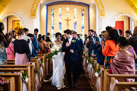 Bride and groom arm in arm walking the aisle of Corpus Christi church in Oxford