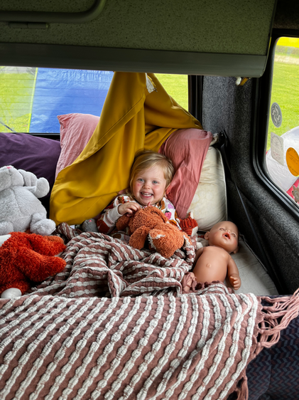 Edie surrounded by her toys in the campervan on holiday
