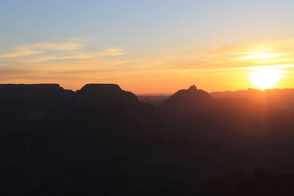 Bright yellow and orange sunrise behind mesa silhouettes