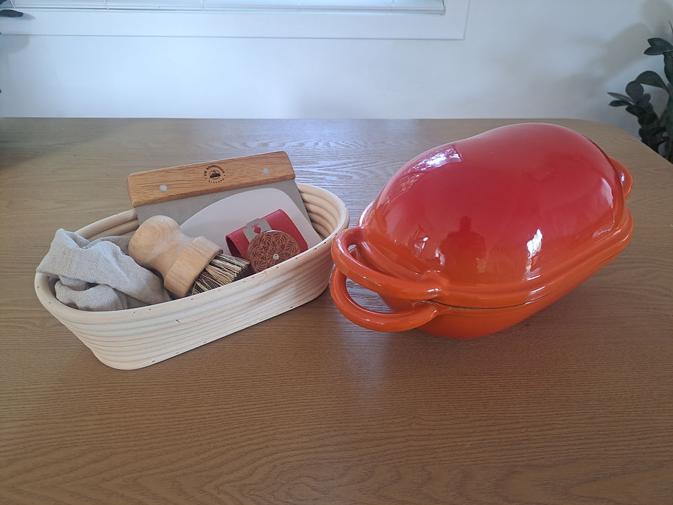 Essential sourdough baking kit featuring orange enamel Dutch oven, rattan banneton, monkey lame, and a natural fibre cleaning