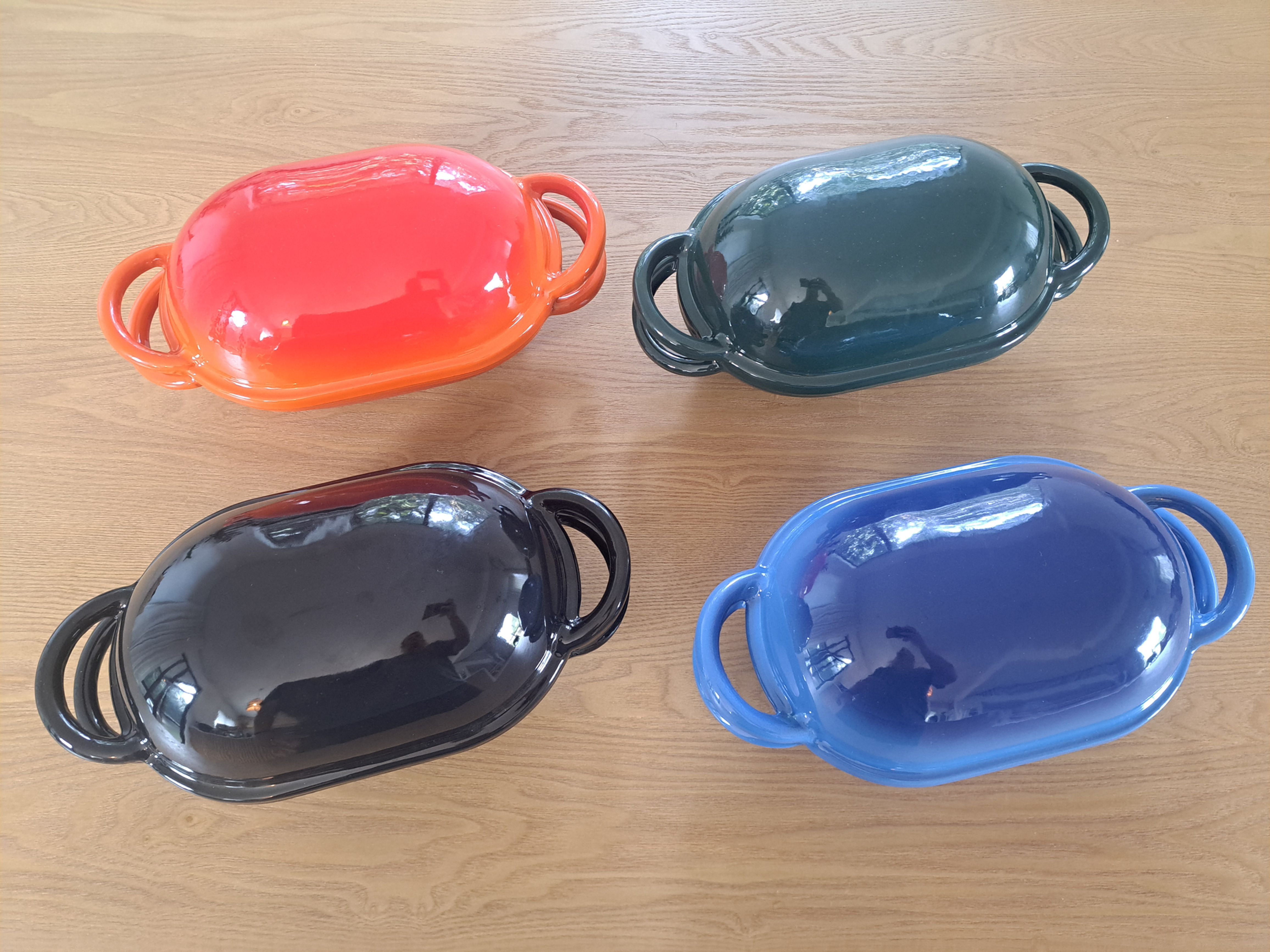 A selection of oval enamel cast iron Dutch ovens showing the range of colors available, suitable for baking sourdough batards