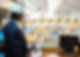 Man in suit and hard hat standing in mezzanine office overlooking warehouse floor full of construction and