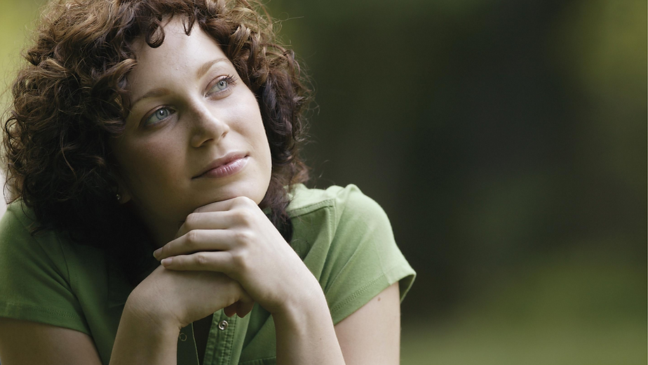 Woman resting her head on her hands, looking peaceful and content. A soft, reflective moment representing calm and emotional wellbeing.