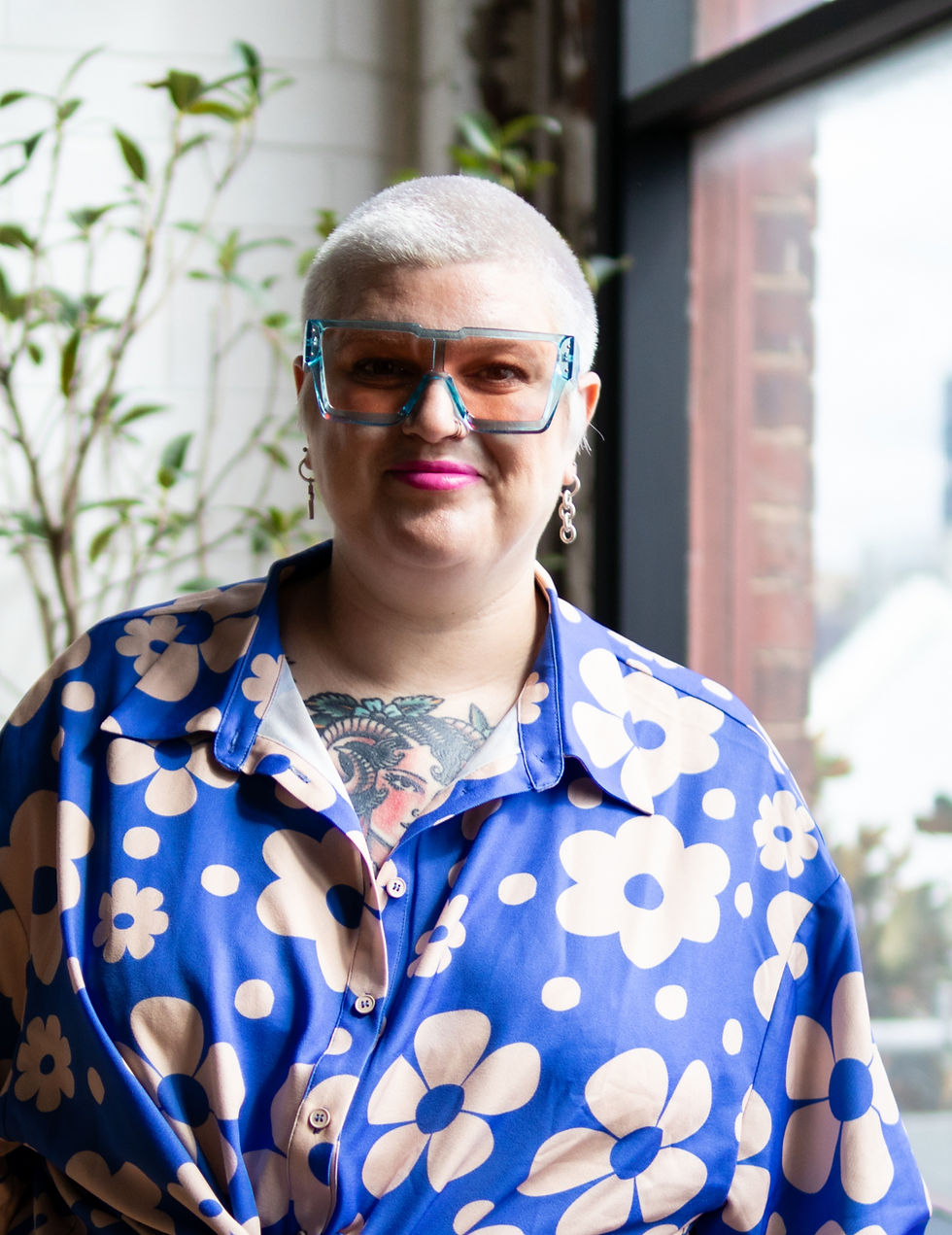 Transparent blue framed and peach lensed sunglasses worn by woman with bleached shaved head