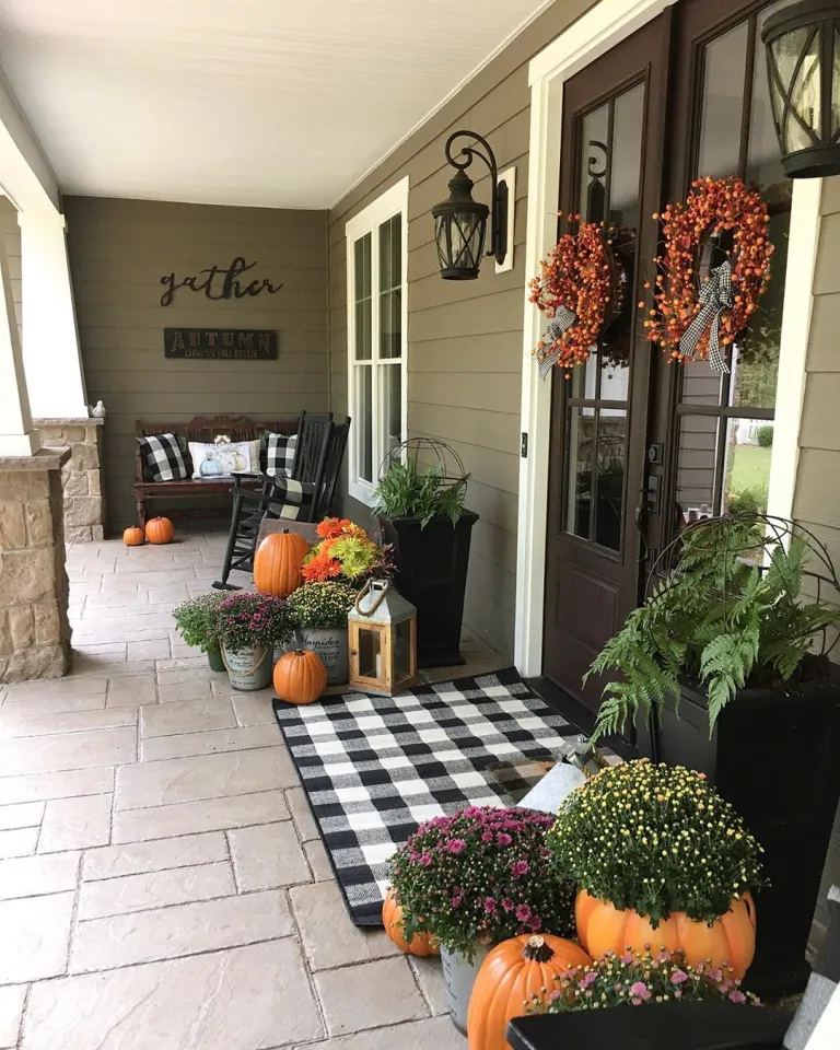 Front door fall decor with pumpkins, plants, lanterns, and door mat