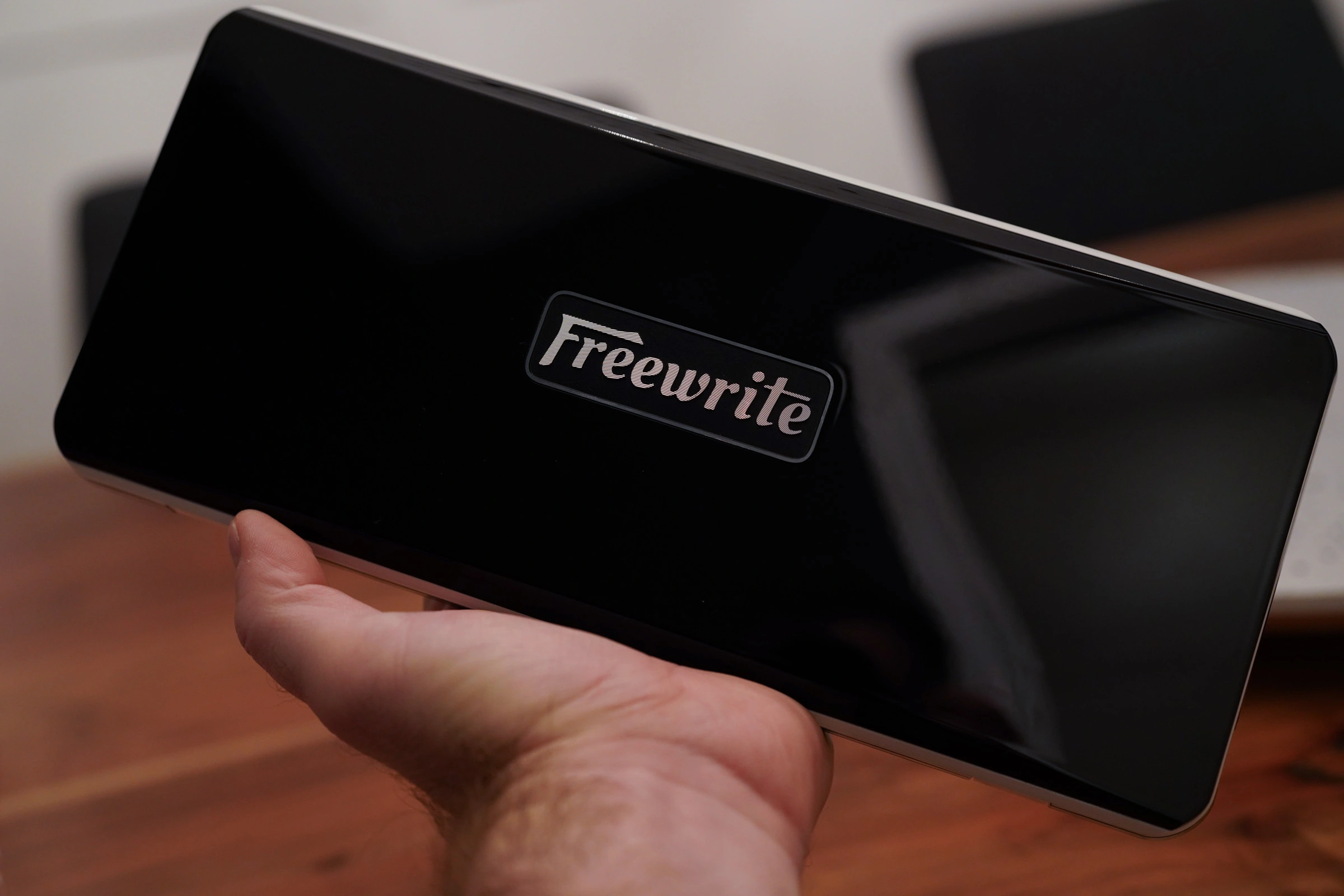 Holding closed Freewrite typewriter with glossy black top and Freewrite logo