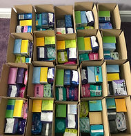A selection of All Yours community period boxes containing disposable period products.