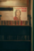 A vintage music collection displayed in a cozy setting, featuring a retro poster of a classic album by İlhan İrem above a shelf lined with cassette tapes.
