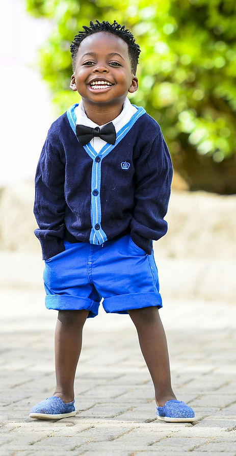 Happy young boy in private school uniform of blue cardigan and bow tie