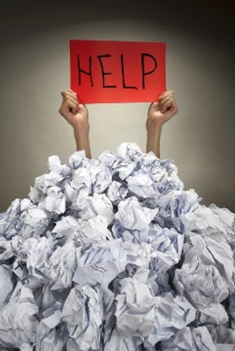 A person holding a HELP sign buried under paper