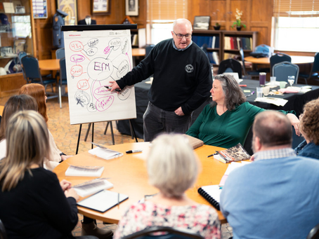 Room full of EfM participants.  White board with EfM at the center and connections to other ideas.