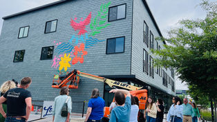 Bus tour guests observe a mural being painted outside Star Lofts in Des Moines.
