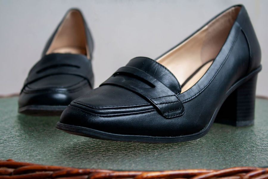 Black leather penny-style loafers with a low block heel on a woman