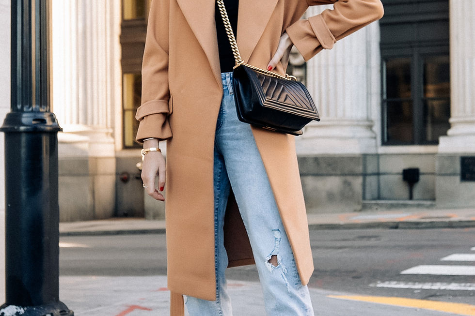 Woman in a camel wool coat with light jeans on a city street