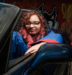 a high school senior portrait in a blue graduation gown with red accents