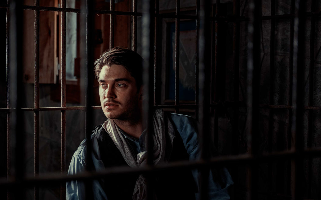a well posed portrait of a man looking out through bars using off camera flash