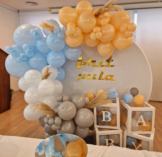 Celebrating joyous beginnings with LuxuryEventsBcn. Picture a circular white background adorned with an array of festive balloons, setting the stage for excitement. Centered within, four sizable cubes unite to spell the word 'BABY,' creating a delightful and visually stunning decor for your special occasion.