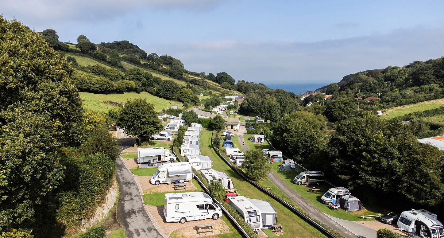 View of park from above showing campsite surrounded by trees and sea