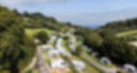 View of park from above showing campsite surrounded by trees and sea