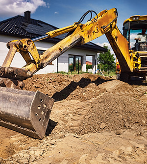 Excavator working at house construction site - digging foundations for modern house. Begin
