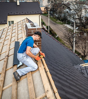 a professional handyman master (roofer) with electric screwdriver covers repairs the roof.