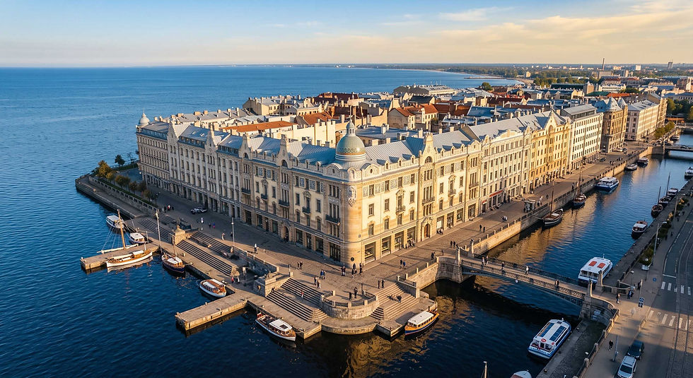 Vista aérea de edificios históricos junto al mar, con muelles, barcos y un canal tranquilo bajo luz dorada.