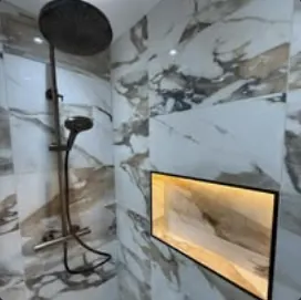 Shower with marble-effect tiles, black rainfall shower and lit recess