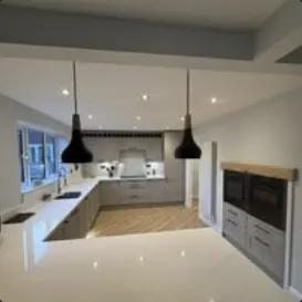 Kitchen with island worktop, black pendant lights and built-in ovens
