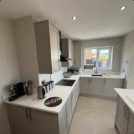 Kitchen with grey units, white worktops and integrated ovens