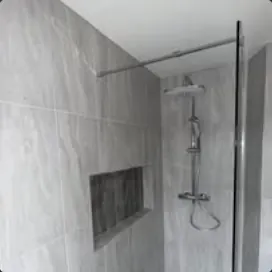 Grey-tiled walk-in shower with recessed shelf