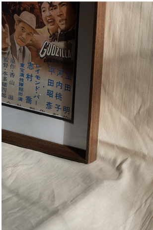 Detailed close-up of a handcrafted walnut picture frame showing crisp mitred corners, a white mount board and premium finishing. Designed for museum-quality presentation and long-term protection of collectible artwork and posters.