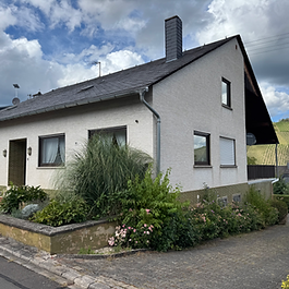 Dieses großzügige Einfamilienhaus in Kindel, einem Ortsteil von Kinheim, wurde 1974 erbaut und bietet viel Platz sowie zahlreiche Nutzungsmöglichkeiten. Auf drei Etagen verteilt sich ein Wohnkonzept, das besonders Familien anspricht und viel Raum für individuelle Gestaltungsideen lässt.
Im Erdgeschoss stehen Ihnen rund 148 m² Wohnfläche zur Verfügung. Hier erwarten Sie ein lichtdurchflutetes Wohnzimmer mit Zugang zum Balkon und herrlichem Ausblick in die Weinberge, ein Esszimmer, drei Schlafzimmer, eine Küche, ein Badezimmer, ein separates Gäste-WC, eine Garderobe sowie ein praktischer Hauswirtschaftsraum. Der Balkon lädt zum Verweilen ein und bietet eine traumhafte Kulisse, um den Tag entspannt ausklingen zu lassen.
Das Dachgeschoss, ebenfalls rund 148 m² groß, befindet sich im Rohbau und kann unkompliziert ausgebaut werden. Dies eröffnet Ihnen vielfältige Möglichkeiten: Ob als Erweiterung für die Familie oder als separate Wohneinheit – hier lässt sich auch problemlos ein Zweifamilienhaus realisieren.
Im Kellergeschoss finden Sie neben einem WC, dem Heizungs- und Abstellraum auch eine gemütliche Bar sowie einen Weinkeller beziehungsweise eine Scheune. Dieser Bereich eignet sich hervorragend für gesellige Abende oder zur Lagerung edler Weine.
Das Haus steht auf einem großzügigen Grundstück mit gepflegtem Garten, der viel Platz zum Entspannen oder Spielen bietet. Auf dem Hof sind zahlreiche Stellplätze vorhanden, zusätzlich gibt es ein praktisches Carport.
Insgesamt präsentiert sich diese Immobilie als ein Haus mit großem Potenzial. Ob als weitläufiges Einfamilienhaus oder als clever aufgeteiltes Zweifamilienhaus – hier haben Sie die Freiheit, Ihre Wohnträume individuell zu gestalten. Die ruhige Lage in Kindel, Kinheim, kombiniert mit dem unverbaubaren Blick in die Weinberge, macht dieses Anwesen zu einer besonders attraktiven Gelegenheit.