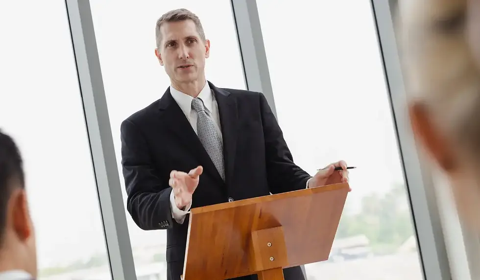 A CEO stands at a podium presenting to a group of executives.
