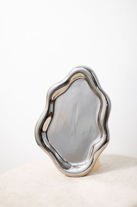 Silver tray with unique wavy edge design displayed on a white surface.