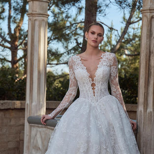 Ivory and light nude Sorella LA26255 lace A-line wedding dress by L’Amour with plunging V-neckline, long sleeves, basque waist, lace appliqués and pockets.