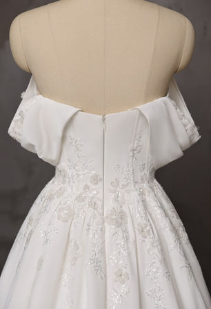 For the curvaceous bride who dreams of a fairy - tale moment! The structured satin bodice, paired with a timeless scoop neckline, creates a flattering silhouette that accentuates the figure beautifully. The flowing chiffon skirt, with a daring slit, lets you move with grace. Detachable draped sleeves are definitely clever design. Delicate floral embroidery at the waist adds a touch of romance. Embrace your beauty and walk down the aisle in this gown that celebrates your curves and your love story.