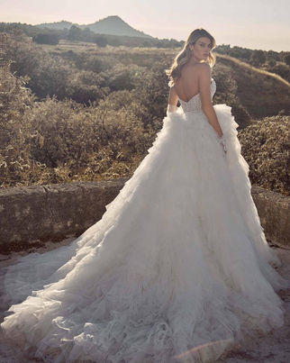 Rivienne STYLE  125248 Dress by Calla Blanche Bridal 
A strapless sparkly wedding dress like Rivienne knows how to steal the spotlight. From the sculpted semi-sweetheart neckline to the curve-hugging sheath silhouette, every inch is designed to dazzle with beaded lace and luminous detailing. For those craving drama, her voluminous detachable tulle overskirt delivers a showstopping moment—soft, romantic, and impossibly grand. Additionally, her matching gloves complete the look with couture-level flair, making this gown a glamorous fantasy from ceremony to reception.
Colors
Ivory/Light Nude (Pictured), Ivory/Ivory

Fabric
Lace, Beaded Lace, Tulle

Silhouette
Sheath

Neckline
Semi Sweetheart, Sweetheart, Strapless

Sleeves
Strapless/Sleeveless

Accessories (May Be Sold Separately)
Detachable Overskirt, Gloves

Style
Sparkly, Romantic, Glamorous, Statement

Size
0-24

Features
New Arrival, Sparkles
