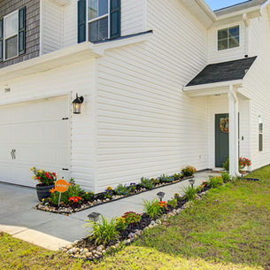 Green front door of a single-family home in Hinesville with landscaped walkway and front garden entrance