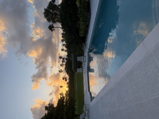 Sunset over a pool on Hutchinson Island Florida with palm trees swaying in the background