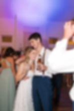 Bride and groom holding each other while swaying on the dance floor with their signature cocktails are in hand