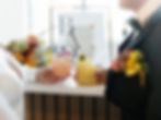 A close up of a bride and groom holding wedding signature cocktails. The groom is holding a summer yellow cocktail and the bride is holding a beachy peach color cocktails