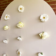 Décoration de baby shower avec fleurs délicates disposées sur un fond clair et minimaliste.