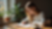 Eye-level view of a woman writing in a journal with a cup of tea nearby