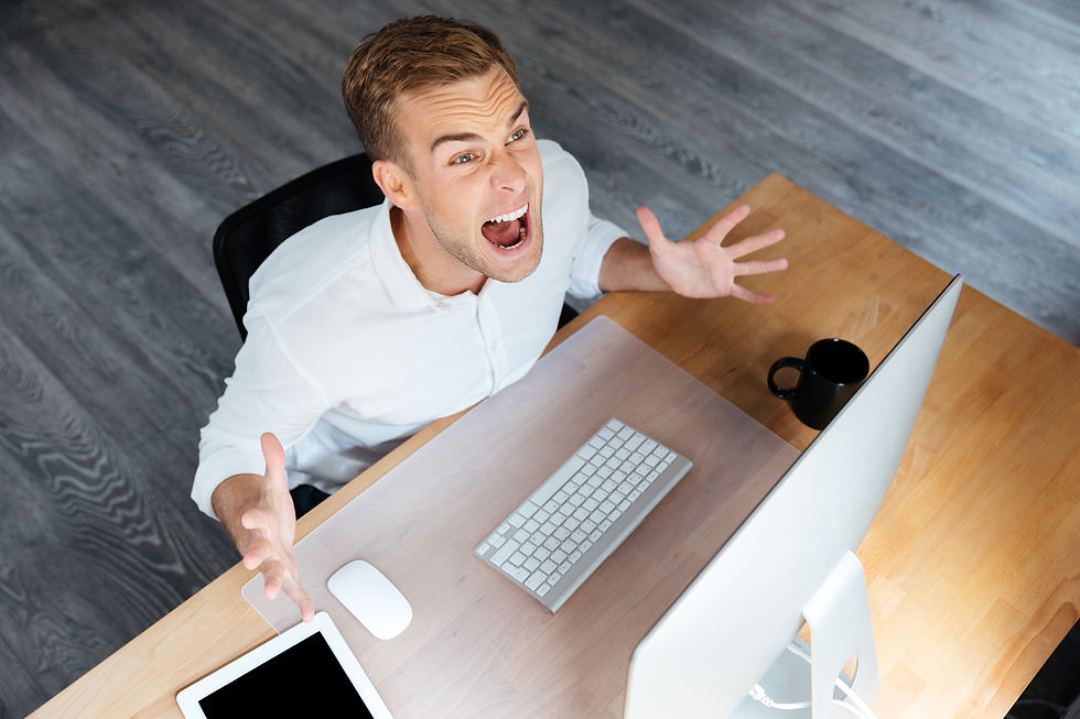 top-view-of-frustrated-young-professional-working-on-computer-and-expressing-frustrati-SBI