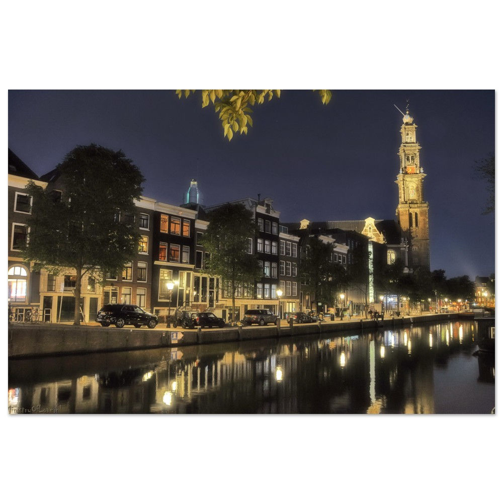 Amsterdam canal at night with illuminated buildings and reflection in water.