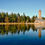 Thumbnail: Tall brick tower reflected in the serene lake water with surrounding trees.