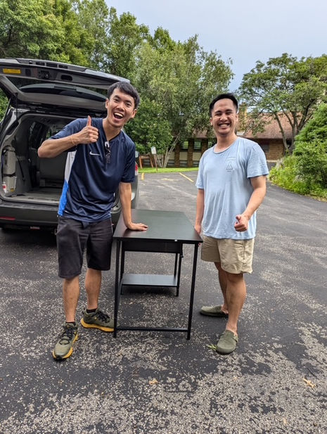 Two students giving a thumbs up when picking up a table