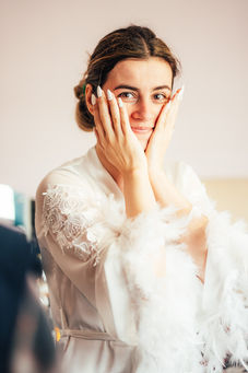 Bride in white robe poses with hands on face. Wedding Photography in Yorkshire.